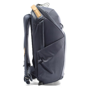 Peak-Design-Everyday-Backpack-Zip-15L-midnight-3 Sivunäkymä Peak Design Everyday Backpack Zip 15L Midnight -repusta, jossa on pehmustetut olkahihnat, ruskehtava nahkakahva ja sivutaskut, pystyasennossa valkoisella pohjalla.