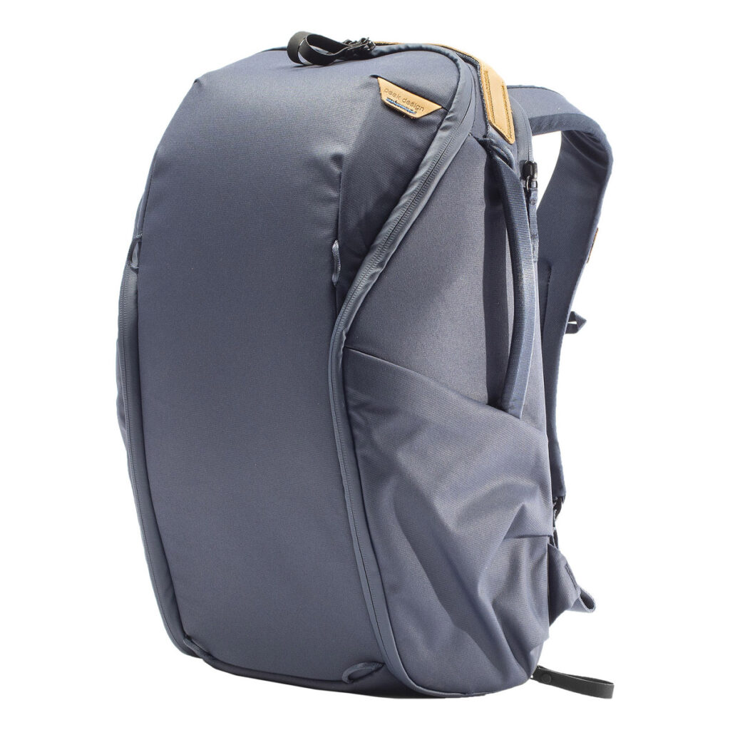 Peak-Design-Everyday-Backpack-Zip-20L-midnight-1 Peak Design Everyday Backpack Zip 20L -kamerareppu, tummansininen, sisältää pehmustetut olkahihnat, yläkahvan, sivutaskun ja ruskehtavan nahkaisen korostuksen vetoketjun kohdalla, ja se on kuvattu pystyasennossa valkoisella pohjalla.