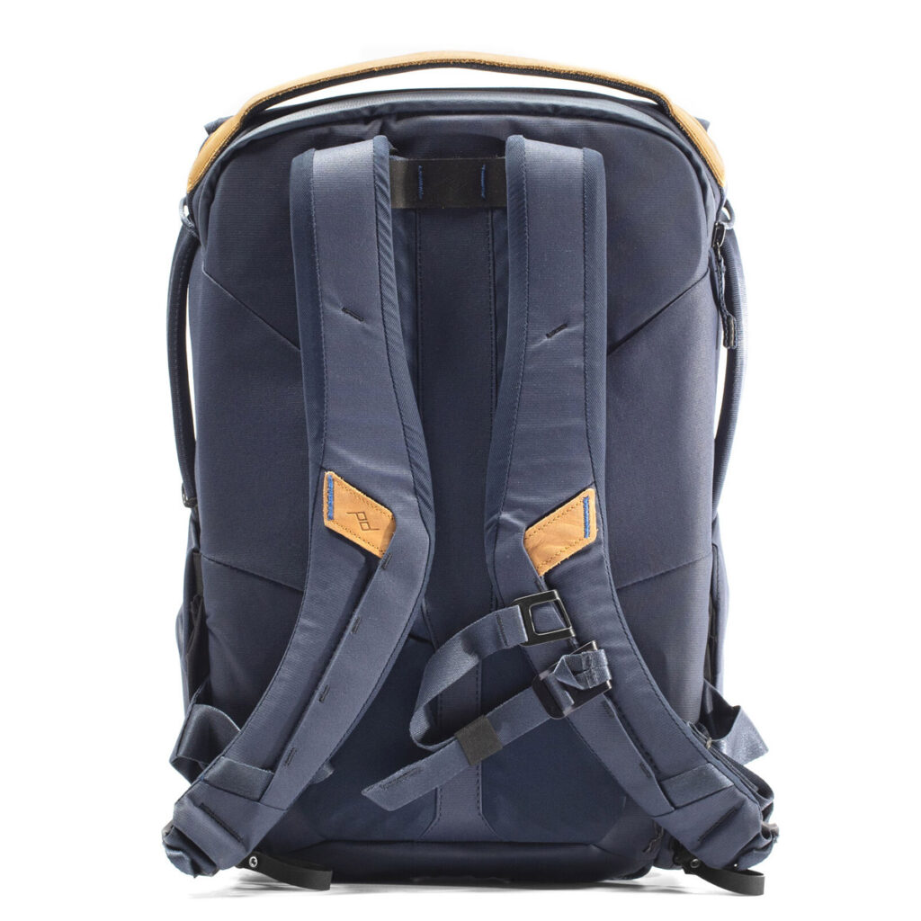 Peak-Design-Everyday-Backpack-v2-20l-midnight-2 Peak Design Everyday Backpack v2 20L -kamerareppu tummansinisessä on kuvattu takaa valkoista taustaa vasten, ja siinä on pehmustetut olkahihnat, ruskehtavat aksenttilaput ja useita säätösolkia.