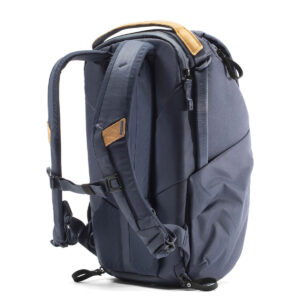 Peak-Design-Everyday-Backpack-v2-20l-midnight-3 Tummansinisessä Peak Design Everyday Backpack v2 20L -kamerareppu, jossa on ruskehtavat nahkakoristeet, pehmustetut olkahihnat, yläkahva ja vetoketjulliset lokerot, kuvassa pystyasennossa valkoisella pohjalla.