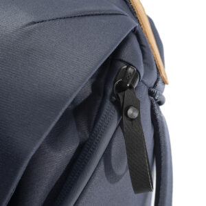 Peak-Design-Everyday-Backpack-v2-20l-midnight-5 Lähikuva Peak Design Everyday Backpack v2 20L -kamerareppu tummansinisessä, jossa korostuu sen tummansininen vetoketju mustalla nahkavetokielekkeellä, kuvioitu kangas ja yksityiskohtaiset tikkaukset valkoista taustaa vasten.