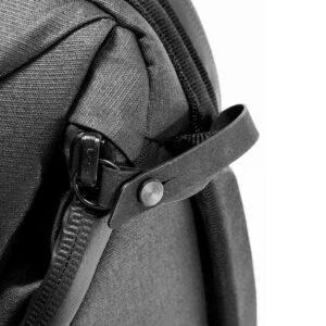 Peak-Design-Everyday-Backpack-v2-30l-black-09 Lähikuva Peak Design Everyday Backpack v2 30L -kamerareppu, musta, jossa näkyy vetoketjun vetoketju, joka on kiinnitetty hihnaan, jossa on painonappi, ja jossa korostuu laukun tukeva musta kangas ja yksityiskohtainen muotoilu.