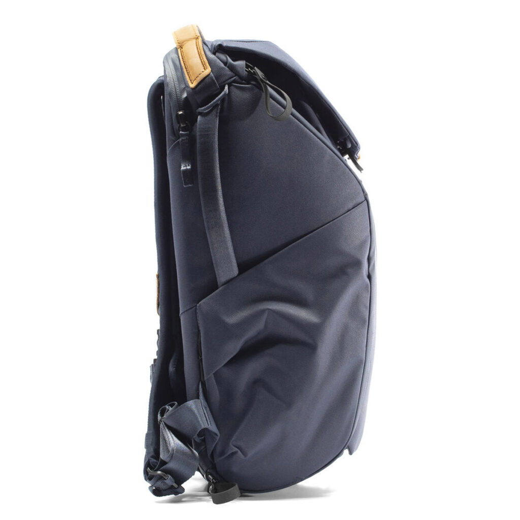 Peak-Design-Everyday-Backpack-v2-30l-midnight-4 Sivunäkymä Peak Design Everyday Backpack v2 30L -kamerareppu tummansinisessä, jossa on pehmustetut olkahihnat, yläkahva tan-aksentilla, sivutasku ja jäsennelty, hieman kaareva muotoilu.