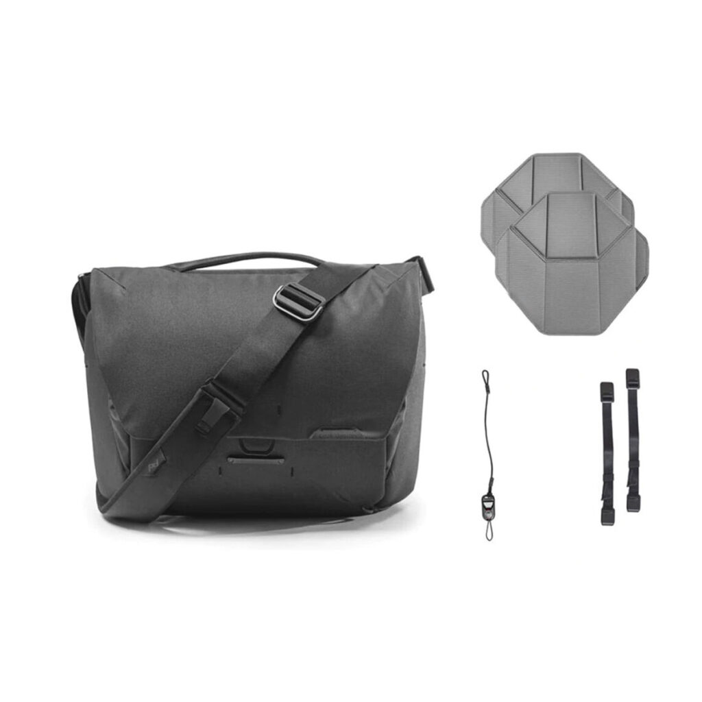 Peak-Design-Everyday-Messenger-13L-v2---Black-5 Peak Design Everyday Messenger 13L V2 mustana on esitetty kahdella kuusikulmaisella insertillä, pienellä hihnalla, jossa on klipsi, ja kahdella lyhyellä mustalla hihnalla, jotka kaikki on sijoitettu valkoiselle taustalle.