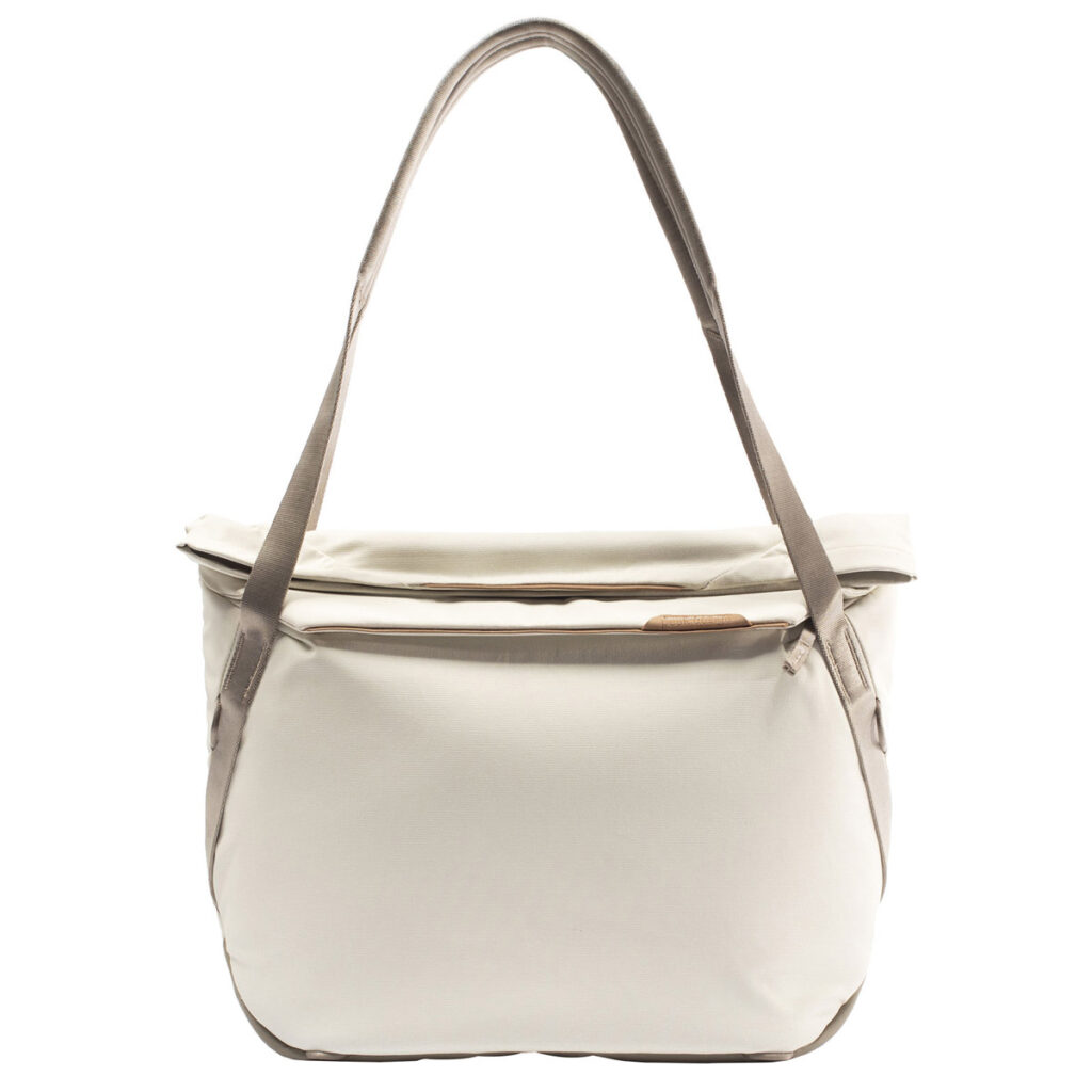 Peak-Design-Everyday-Tote-15l-bone-1 Peak Design Everyday Tote 15L v2 Bone -mallissa on vaaleanruskeat hihnat, vetoketjullinen etutasku ja tilava päälokero. Sen yksinkertainen, moderni muotoilu erottuu valkoista taustaa vasten.