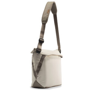 Peak-Design-Everyday-Tote-15l-bone-2 Peak Design Everyday Tote 15L v2 Bone -laukussa on suorakulmainen muoto, säädettävä ruskea olkahihna ja läppäsuljenta, kuvassa valkoisella pohjalla.