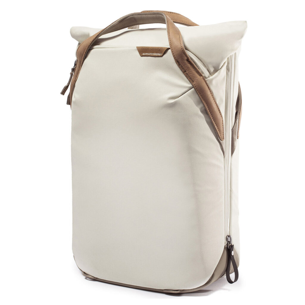 Peak-Design-Everyday-Totepack-20l-bone-3 Peak Design Everyday Totepack 20L v2 in Bone on moderni, minimalistinen vaaleanbeige reppu, jossa on ruskehtavat nahkakahvat sekä sivu- ja ylävetoketjut, kuvassa valkoista taustaa vasten.