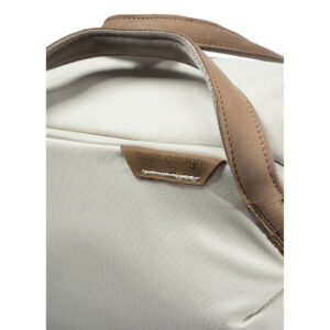 Peak-Design-Everyday-Totepack-20l-bone-4 Lähikuva Peak Design Everyday Totepack 20L v2 Bone -mallistosta, jossa on vaalean beige kangas, ruskea nahkakahva, reunus ja ommeltu Peak Design -merkki. Laukussa on selkeät linjat ja minimalistinen muotoilu.