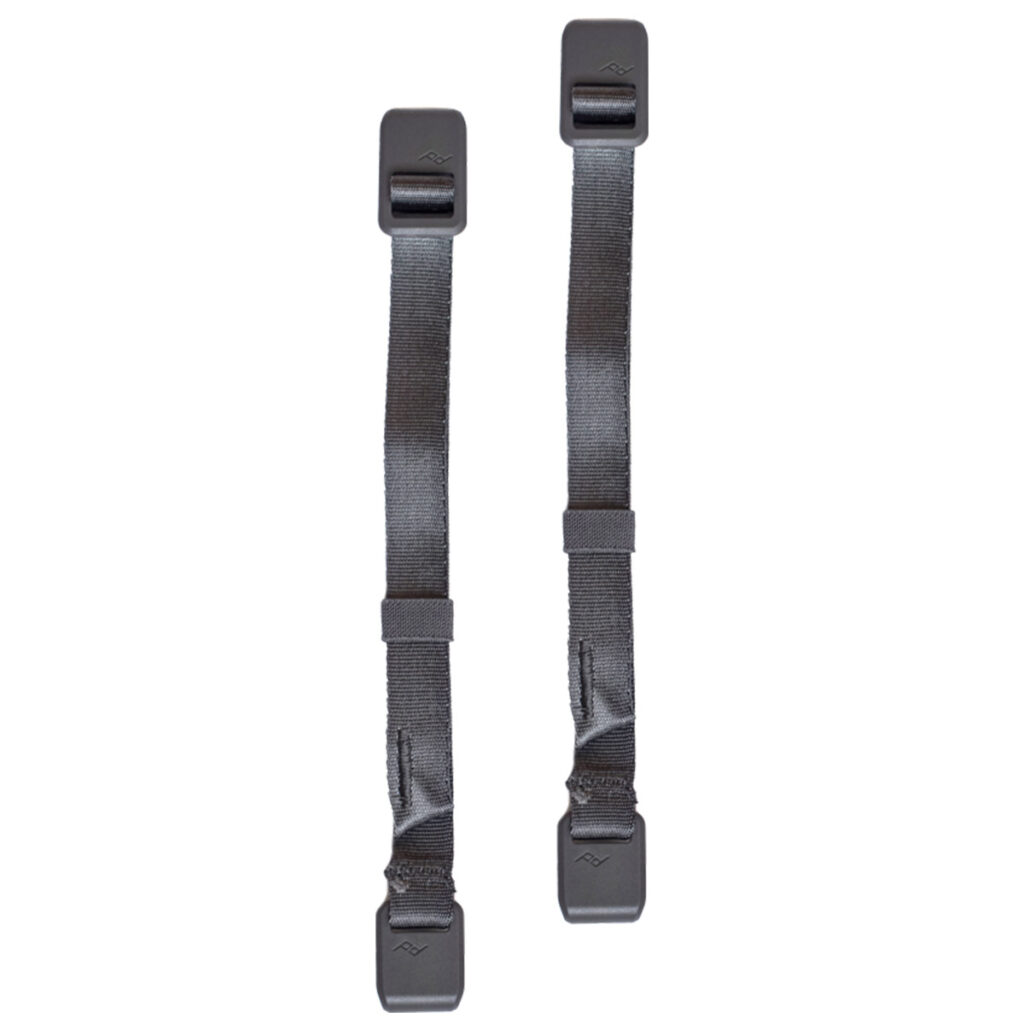 Peak-Design-External-Carry-Strap-V2-short-ash-1 Kaksi Peak Design Spareparts V2 -ulkoista kantohihnaa (lyhyt, tuhka), joissa on mustat säädettävät nailon- ja muovikiinnikkeet molemmissa päissä, pystysuorassa vierekkäin valkoisella pohjalla.