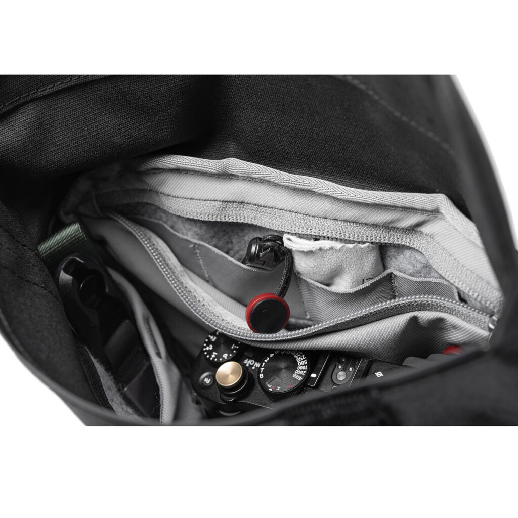 Peak-Design-Field-Pouch-V2-black-4 Lähikuva Peak Design Field Pouch V2 -laukusta (musta), jossa näkyy järjestetyt lokerot ja kamera, joka on osittain näkyvissä tarvikkeiden joukossa.