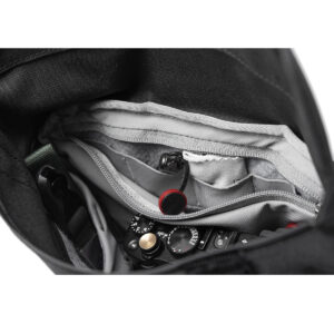 Peak-Design-Field-Pouch-V2-black-4 Lähikuva Peak Design Field Pouch V2 -laukusta (musta), jossa näkyy järjestetyt lokerot ja kamera, joka on osittain näkyvissä tarvikkeiden joukossa.