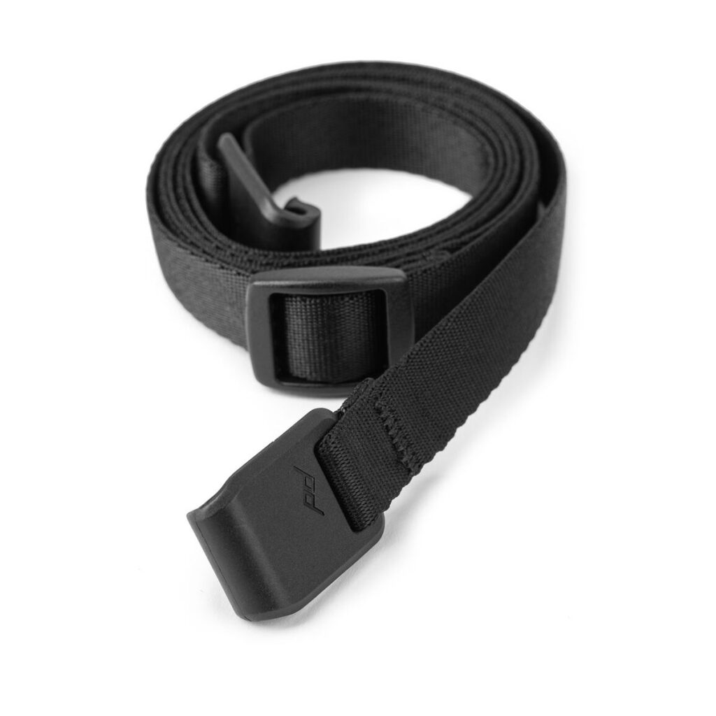 Peak-Design-Field-Pouch-V2-black-7 Peak Design Field Pouch V2 - Black -mustassa on musta nailonhihna, jossa on suorakulmainen muovisolki ja kulmikas muovinen päätykappale valkoisella pohjalla.
