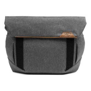 Peak-Design-Field-Pouch-V2-charcoal-2 Peak Design Field Pouch V2 in Charcoal -laukussa on harmaa kangasmalli, jossa on taittuva yläosa, mustat etuhihnat ja pieni ruskea nahkalogo lähellä yläosaa.