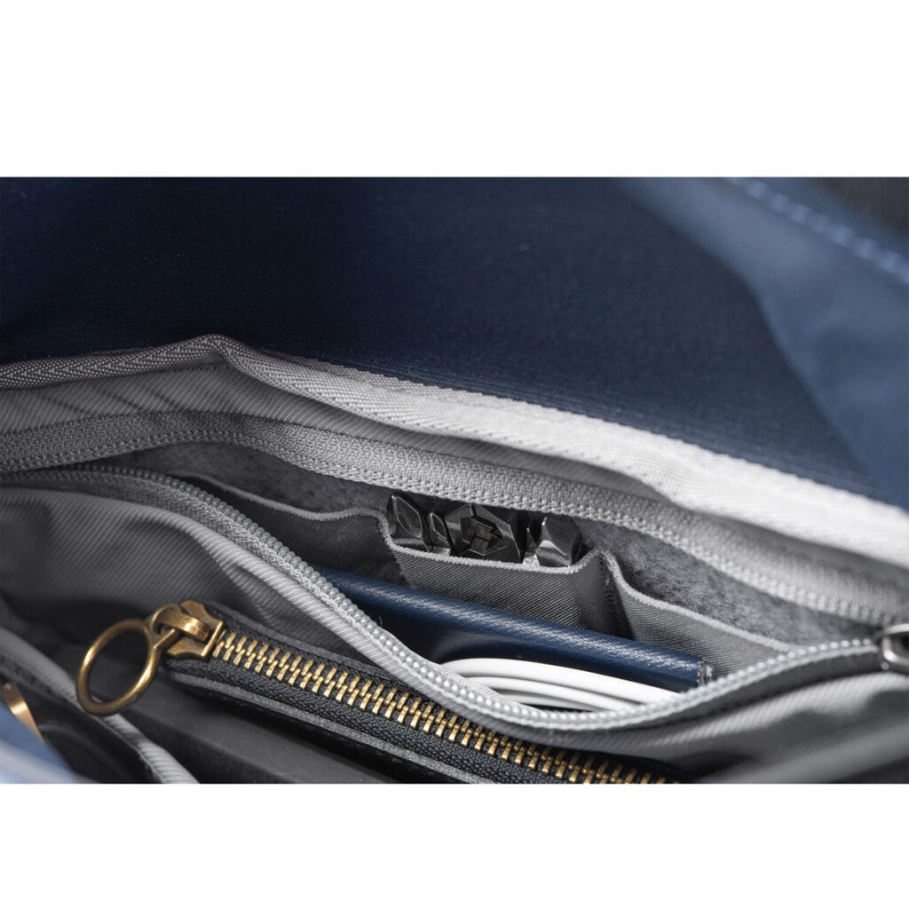 Peak-Design-Field-Pouch-V2-midnight-4 Lähikuva Peak Design Field Pouch V2 - Midnight -laukusta, jossa on sininen kangasvuori, kultainen vetoketju, vetoketjullinen tasku ja järjestetyt lokerot, joihin mahtuvat siististi kaapelit ja muistikirja.