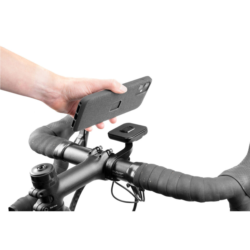 Peak-Design-Mobile-Bike-Mount-8 Käsi kiinnittää älypuhelimen Peak Design Mobile Out Front Bike Mount -pyöräkiinnikkeeseen, joka on polkupyörän ohjaustankoon kiinnitettävä suorakulmainen kiinnike, joka on suunniteltu puhelimen turvalliseen kiinnittämiseen.