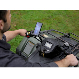 Peak-Design-Mobile-Motorcycle-ball-adapter-6 Kuljettaja käyttää Peak Design Mobile Motorcycle Mount 1" Ball Adapteria pitämään älypuhelinta ATV:n keskimmäisessä ohjaustangossa, näyttö näkyvissä, ja avaimet sytytysvirrassa digitaalinäytön vieressä.