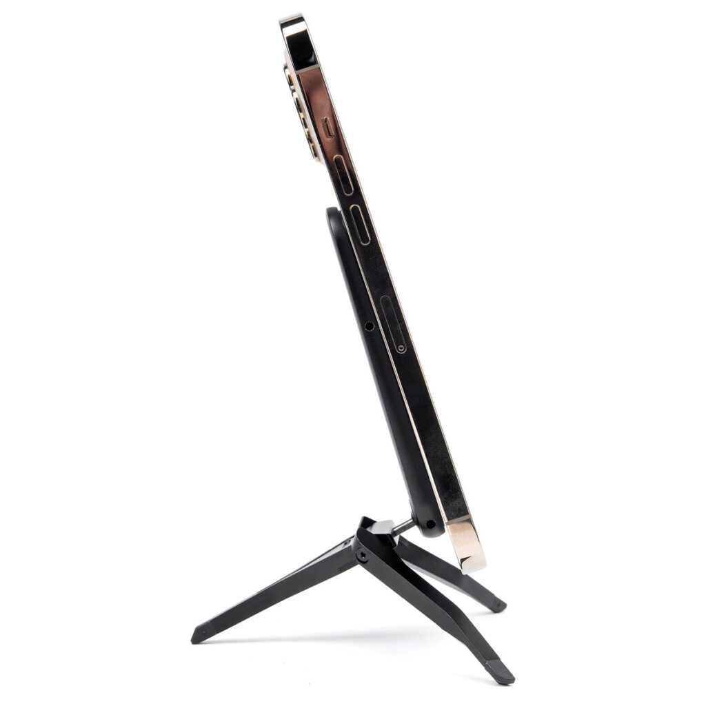 Peak-Design-Mobile-Tripod-4 Sivukuva Peak Design Mobile Tripod - Black -jalustasta, jossa ohut laite on pystyssä valkoista taustaa vasten, korostaa jalustan kokoontaitettavaa muotoilua ja siirrettävyyttä. Myös laitteen ohut profiili ja reunimmaiset portit näkyvät.