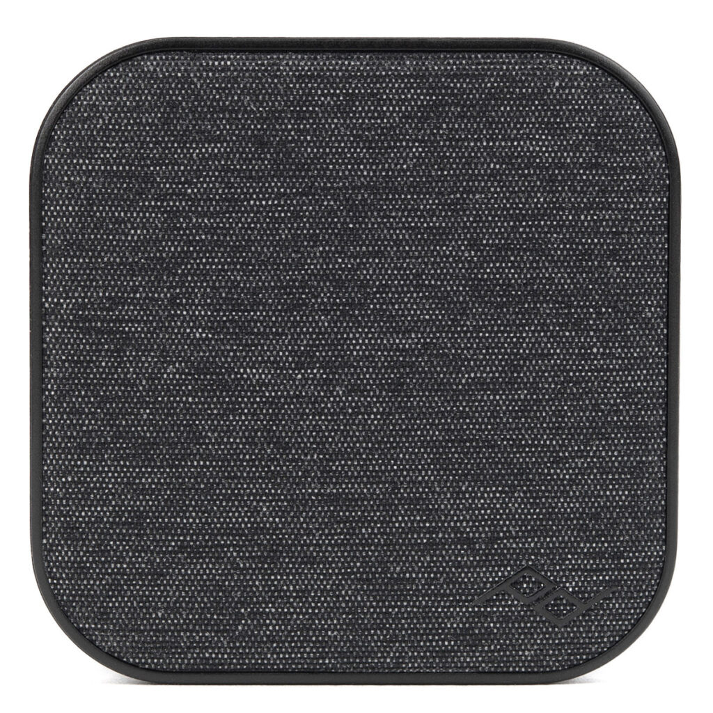 Peak-Design-Mobile-Wall-Mount-Charcoal-1 Neliön muotoinen Peak Design Mobile Wall Mount -seinäkiinnike hiilenväristä kangasta, jossa on pyöristetyt kulmat, kuvassa edestäpäin. Pieni logo näkyy oikeassa alakulmassa.