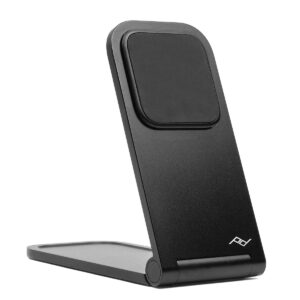 Peak-Design-Mobile-Wireless-Charging-Stand-1 Peak Design Mobile Wireless Charging Stand on musta, kokoontaitettava, siinä on minimalistinen muotoilu, jossa on pieni valkoinen geometrinen logo lähellä pohjaa, ja se on kuvassa pystyssä valkoisella pohjalla.