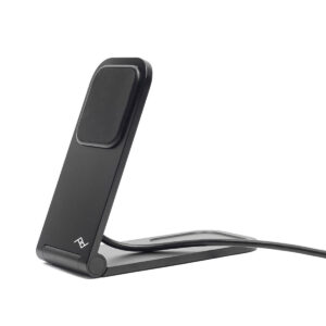 Peak-Design-Mobile-Wireless-Charging-Stand-2 Peak Design Mobile Wireless Charging Stand on tyylikäs ja musta, ja siinä on kulmikas muotoilu, jossa on litteä latausalusta ja liitetty kaapeli, ja se on sijoitettu valkoista taustaa vasten.