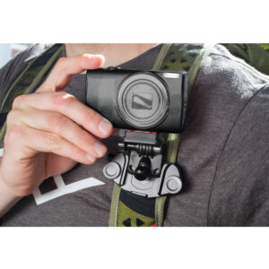 Peak-Design-POV-Kit4 Harmaaseen paitaan ja reppuun pukeutunut henkilö pitää mustaa kameraa, joka on kiinnitetty reppuhihnaan Peak Design POV Kit for Capture -laitteella.