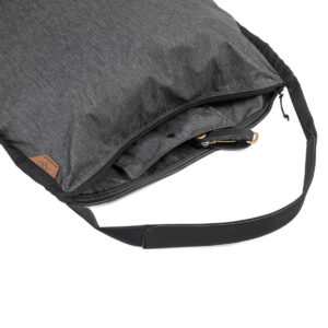Peak-Design-Packable-Tote---Charcoal3 Lähikuva Peak Design Packable Tote in Charcoal, jossa on musta säädettävä hihna, osittain auki vetoketju näyttää sisätasku ja ulkopuolinen nahka laastari.