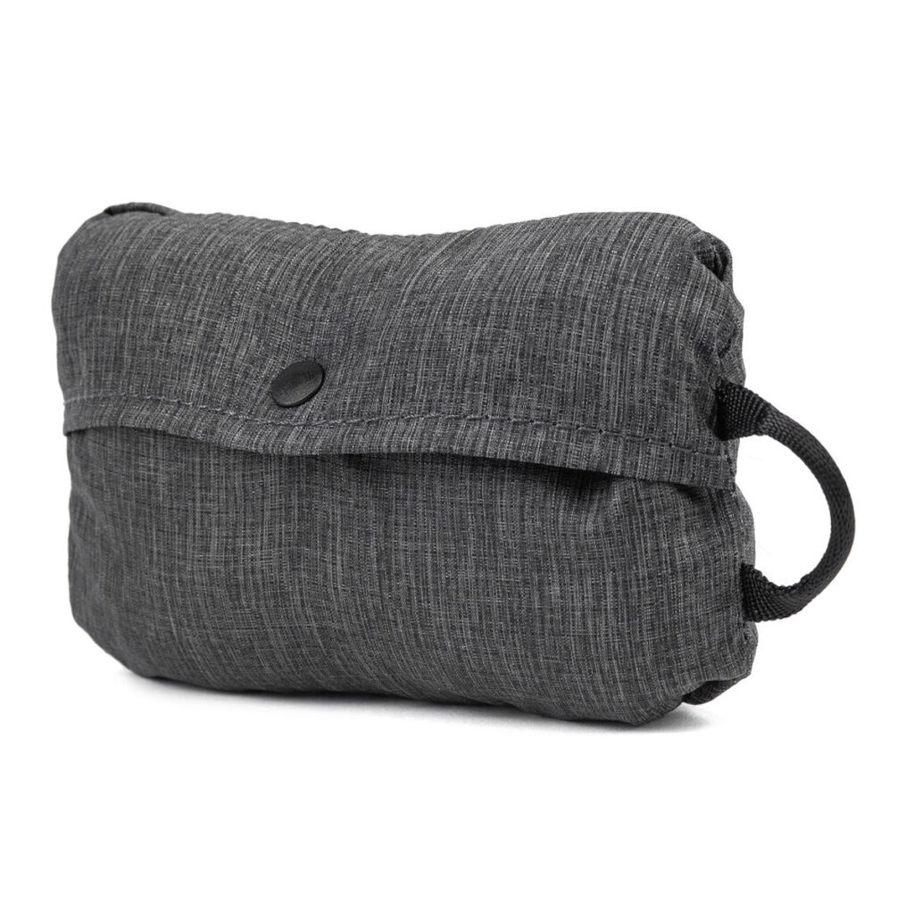 Peak-Design-Packable-Tote---Charcoal4 Peak Design Packable Tote in Charcoal on kompakti, suorakaiteen muotoinen kangaspussi, jossa on napitettu läppä ja musta silmukkakahva valkoista taustaa vasten.