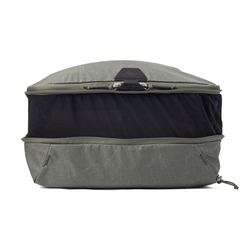 Peak-Design-Packing-Cube-medium--Sage3 Peak Design Packing Cube Medium in Sage on harmaa, suorakulmainen matkanjärjestäjä, jossa on keskellä vetoketjullinen verkkolokero ja kangaspaneelit ylä- ja alapuolella valkoisella pohjalla.