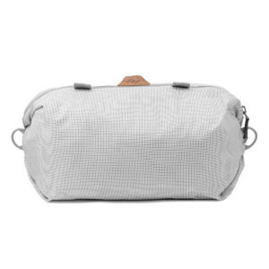 Peak-Design-Shoe-Pouch---Raw1 Peak Design Shoe Pouch - Raw on vaaleanharmaa vetoketjullinen pussi, jossa on kuvioitu kuvio, kaksi sivulenkkiä ja pieni ruskea aksenttilappu päällä valkoisella pohjalla.