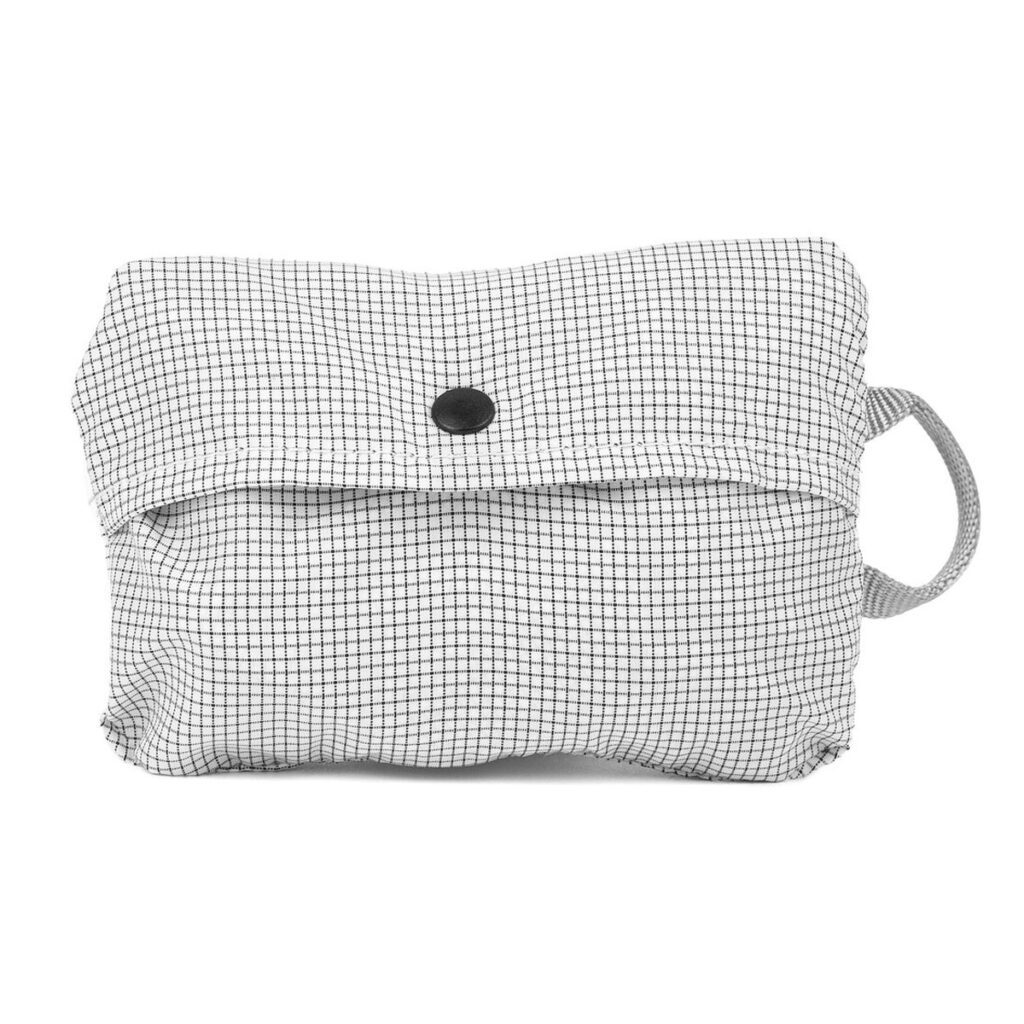 Peak-Design-Shoe-Pouch---Raw4 Peak Design Shoe Pouch - Raw on pieni suorakaiteen muotoinen pussi, jossa on mustavalkoinen ruudukkokuvio, etuläppä mustalla nappisuljella ja oikeanpuoleinen silmukkakahva.