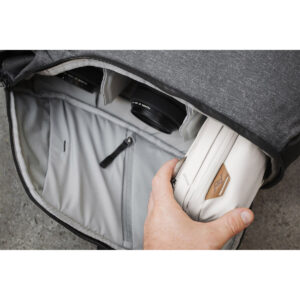 Peak-Design-Tech-Pouch-Bone-5 Käsi asettaa Peak Design Tech Pouch - Bone -laukun harmaaseen reppuun, jossa on järjestettyjä lokeroita, mukaan lukien kaksi kameran objektiivia laukun sisällä.