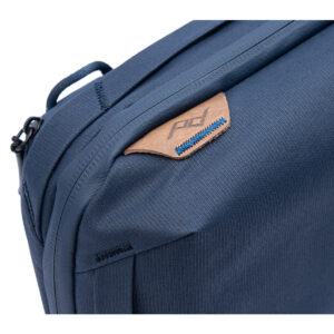 Peak-Design-Tech-Pouch-Midnight-3 Lähikuva Peak Design Tech Pouch - Midnight -laukusta, jossa korostuu sininen kangas, ruskehtava nahkainen korostus sinisillä tikkauksilla ja kohokuvioitu PD-logo vetoketjun vieressä, mikä tuo esiin sen ensiluokkaisen rakenteen ja muotoilun.