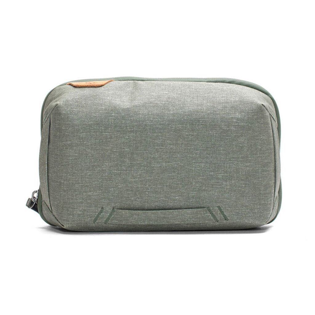 Peak-Design-Tech-Pouch-Sage-1 Peak Design Tech Pouch in Sage on suorakulmainen, vaaleanharmaanvihreä matkapussi, jossa on minimalistinen muotoilu, vasemmanpuoleinen vetoketju ja hienovaraiset tikkaukset edessä.
