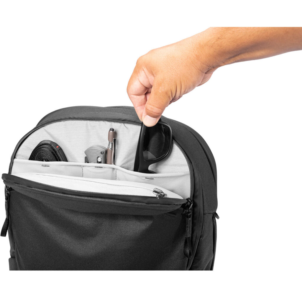 Peak-Design-Travel-Backpack-30L-black5 Käsi asettaa mustat aurinkolasit Peak Design Travel Backpack 30L -kamerareppu, musta, jonka taskuihin on järjestetty siististi erilaisia tavaroita.