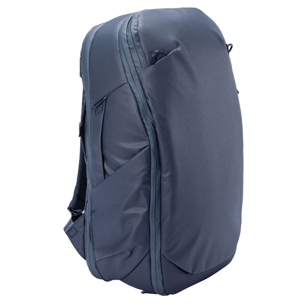 Peak-Design-Travel-Backpack-30L-midnight1 Peak Design Travel Backpack 30L -kamerareppu tummansinisessä värissä on minimalistinen ulkoasu, jossa on sivutaskut, vetoketju ylhäällä ja pehmustetut olkahihnat, ja se on kuvassa pystyssä valkoista taustaa vasten.