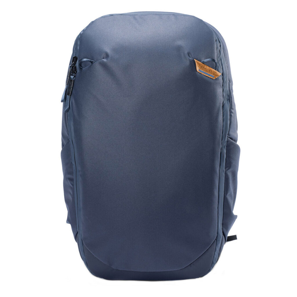 Peak-Design-Travel-Backpack-30L-midnight2 Peak Design Travel Backpack 30L -kamerareppu, tummansininen on tyylikäs, tummansininen reppu, jossa on sileä etuosa, sivutaskut, vetoketju ylhäällä vasemmalla ja pieni ruskea logolaastari oikeassa yläkulmassa. Kuvattu pystyasennossa valkoista taustaa vasten.