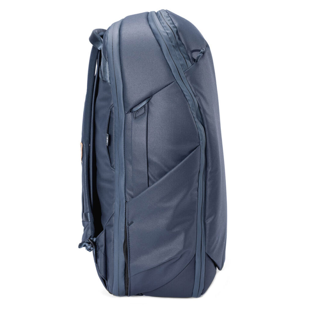 Peak-Design-Travel-Backpack-30L-midnight3 Peak Design Travel Backpack 30L -kamerareppu tummansinisessä värissä sivukuvassa, jossa korostuvat sen useat vetoketjut, lokerot, pehmustetut hihnat ja tyylikäs moderni muotoilu.