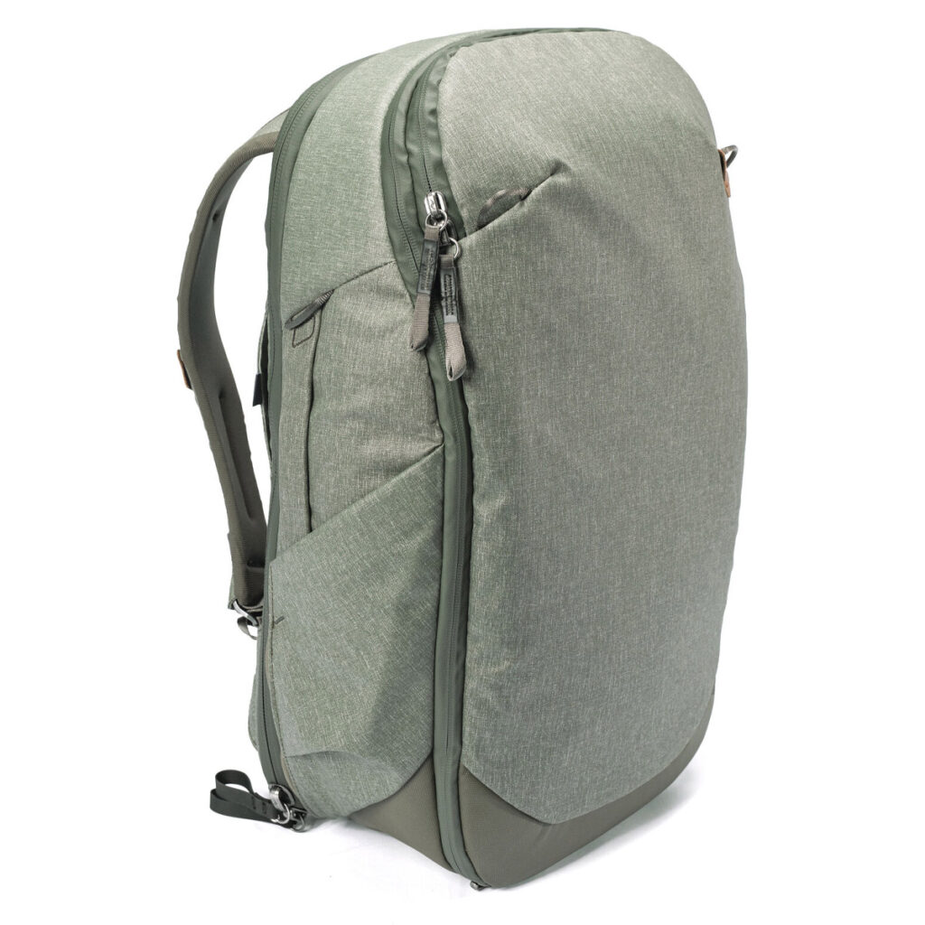 Peak-Design-Travel-Backpack-30L-sage1 Vaaleanvihreässä Peak Design Travel Backpack 30L -kamerareppussa on useita vetoketjullisia lokeroita, pehmustetut olkahihnat ja sivutaskut, kuvassa pystyssä valkoista taustaa vasten.