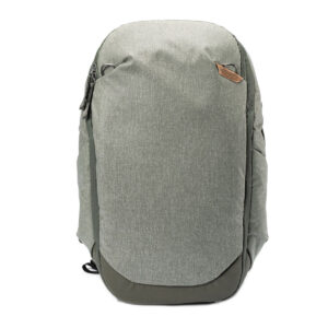 Peak-Design-Travel-Backpack-30L-sage2 Vaaleanvihreässä Peak Design Travel Backpack 30L -kamerareppu on minimalistinen, strukturoitu malli, jossa on vetoketjullinen etutasku ja pieni ruskea korostus, joka näkyy pystyssä valkoista taustaa vasten.