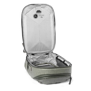 Peak-Design-Travel-Backpack-30L-sage4 Peak Design Travel Backpack 30L -kamerareppu, vaaleanvihreä, seisoo pystyasennossa, kun sen päälokero on avattu vetoketjuineen, jolloin paljastuu vaaleanharmaa sisustus, jossa on taskuja ja järjestysosioita. Kansi nojaa taaksepäin, jotta siihen pääsee helposti käsiksi.