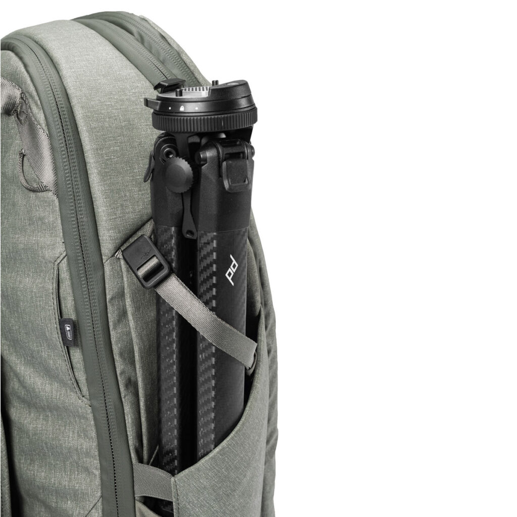 Peak-Design-Travel-Backpack-30L-sage6 Vaaleanvihreä Peak Design Travel Backpack 30L -reppu, jonka sivutaskussa on musta hiilikuituinen jalusta, joka korostaa vetoketjua ja kankaan rakennetta.