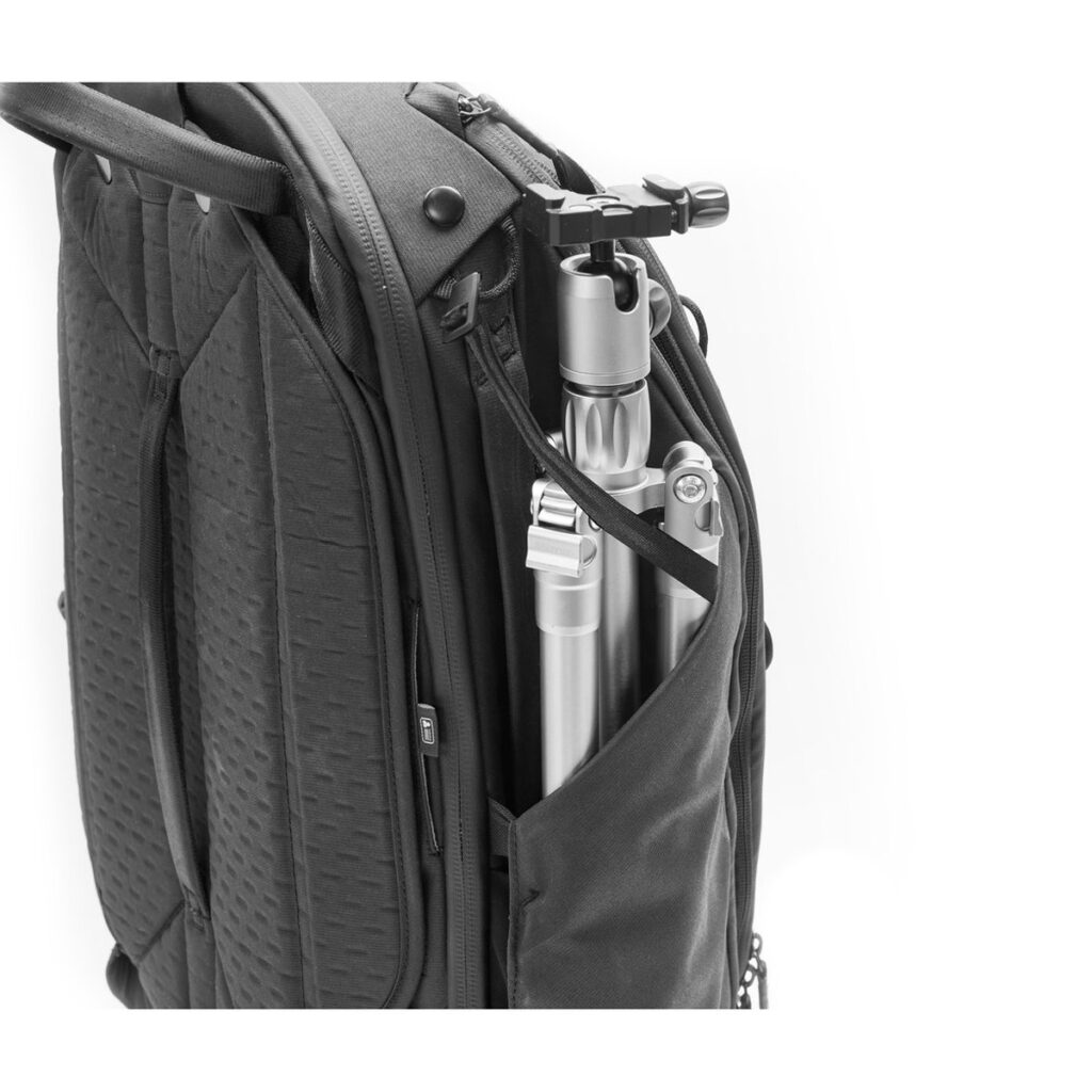 Peak-Design-Travel-Backpack-45L-black06 Peak Design Travel Backpack 45L -kamerareppu, musta, sisältää vetoketjullisen sivutaskun, johon mahtuu kokoontaitettu hopeinen kolmijalka, mikä osoittaa sen kapasiteetin valokuvausvälineiden kuljettamiseen.
