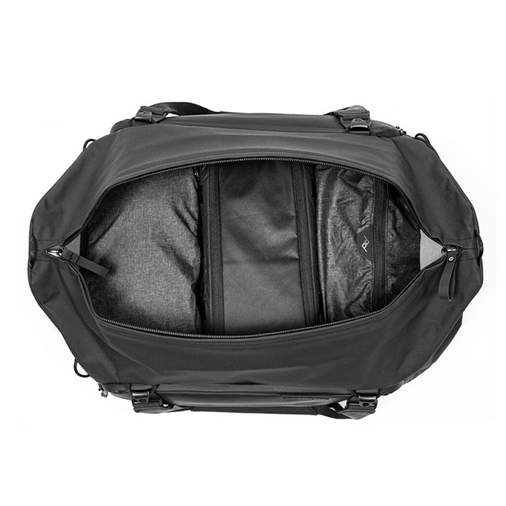 Peak-Design-Travel-Duffel-35l-black-3 Peak Design Travel Duffel 35L -matkalaukku mustana näkyy ylhäältäpäin päävetoketju auki, jolloin tilava, tyhjä sisätila ja useita lokeroita paljastuu.