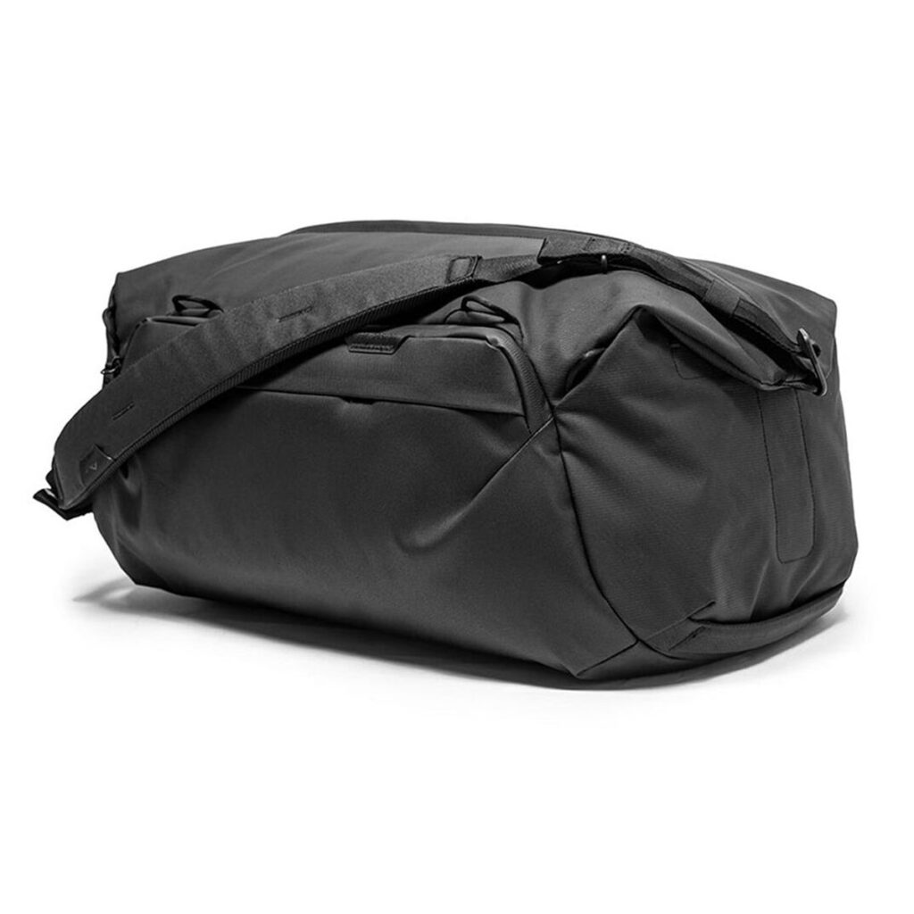 Peak-Design-Travel-Duffel-35l-black-4 Peak Design Travel Duffel 35L - Black on tilava duffel-laukku, jossa on olkahihna ja useita vetoketjullisia lokeroita ja joka on esillä valkoisella pohjalla.