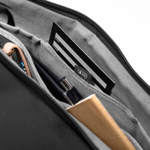 Peak-Design-Travel-Duffel-35l-black-5 Lähikuva Peak Design Travel Duffel 35L - Black -mallin järjestäytyneestä sisätilasta, jossa kynät, muistikirja, latauskaapelit ja mustavalkoinen kortti ovat siististi erillisissä lokeroissa.