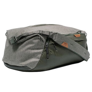 Peak-Design-Travel-Duffel-35l-sage-4 Peak Design Travel Duffel 35L Sage -mallistossa on harmaan ja tummanvihreän sävyjä, leveä säädettävä olkahihna, vetoketjulokeroita ja ruskea logolaastari sivulla valkoista taustaa vasten.