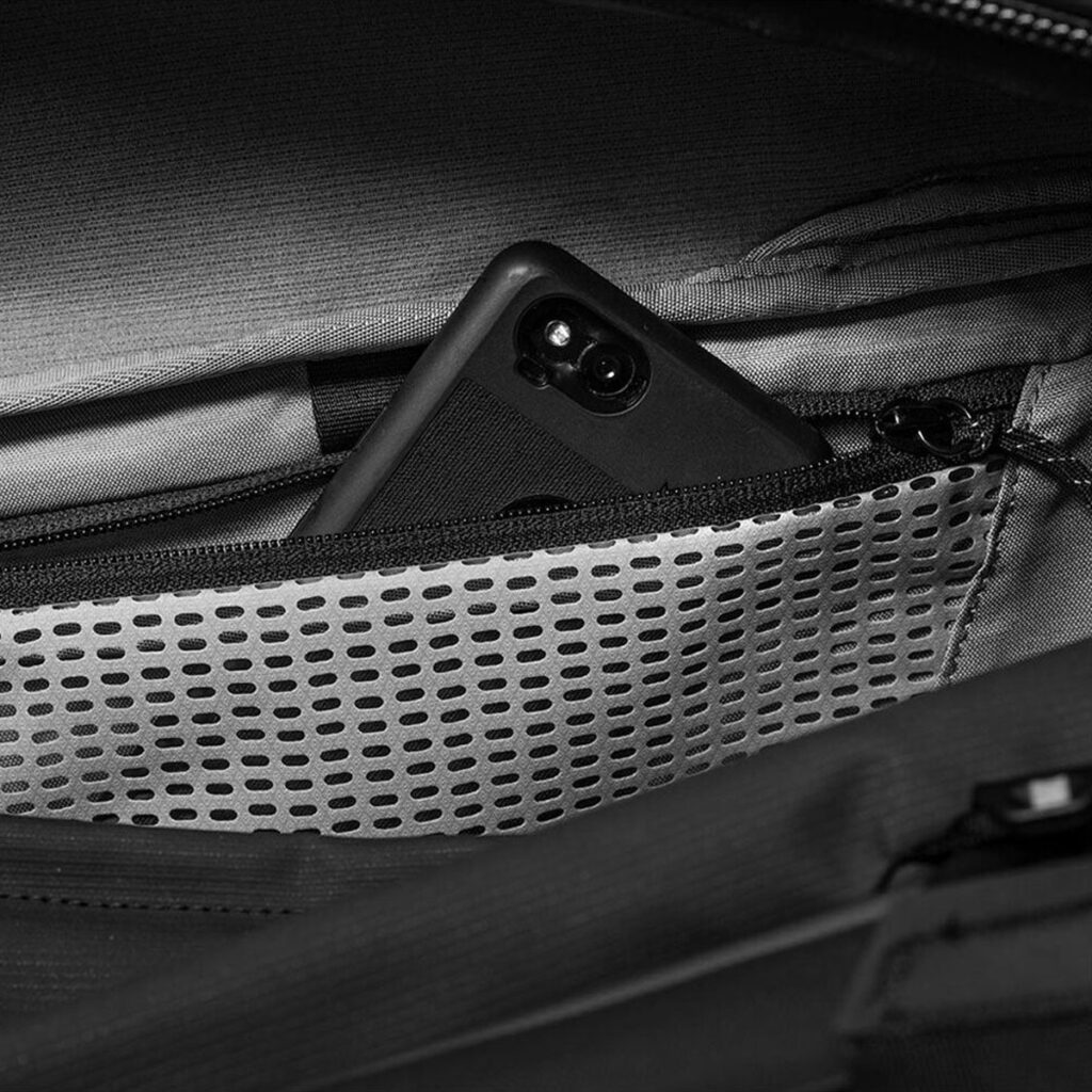 Peak-Design-Travel-Duffel-65l-black-4 Musta älypuhelin on osittain piilotettu vetoketjullisen verkkotaskun sisään Peak Design Travel Duffel 65L - Black.