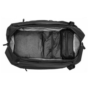Peak-Design-Travel-Duffelpack-65l-black-04 Ylhäältä alaspäin suuntautuva näkymä Peak Design Travel Duffelpack 65L -matkarepusta, joka on pakattu siististi harmailla vaatteilla ja mustalla vetoketjullisella pussilla ja jossa näkyy sen järjestetty päälokero ja sivutaskut.