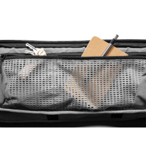Peak-Design-Travel-Duffelpack-65l-black-05 Lähikuva Peak Design Travel Duffelpack 65L - Blackin verkkovetoketjullisesta taskusta, joka on osittain auki ja näyttää avaimet, pienen muistikirjan ja kynän.