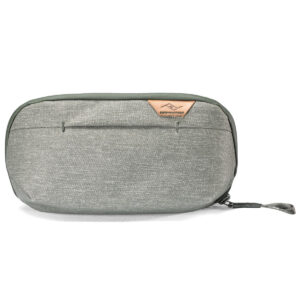 Peak-Design-Wash-Pouch-Small-Sage1 Peak Design Wash Pouch Small -pesupussissa on vetoketjullinen kangasmalli, jossa on etutasku ja pieni ruskehtava nahkainen logokorostus valkoisella pohjalla.
